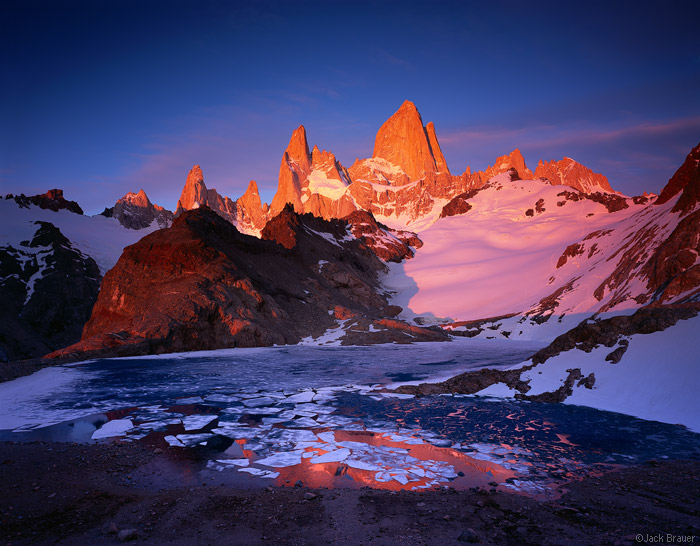 Brilliant sunrise alpenglow on Chaltén (aka Monte Fitz Roy) and Cerro Poincenot, as seen from Laguna de los Tres. Parque Nacional los Glaciares, Argentina - November.